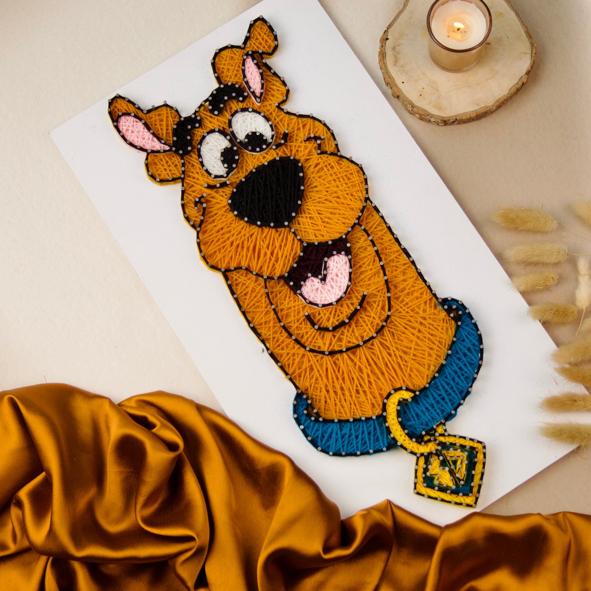 Cute Scooby-Doo yarn and nail art design on white board, ideal for kids' rooms and fun spaces.