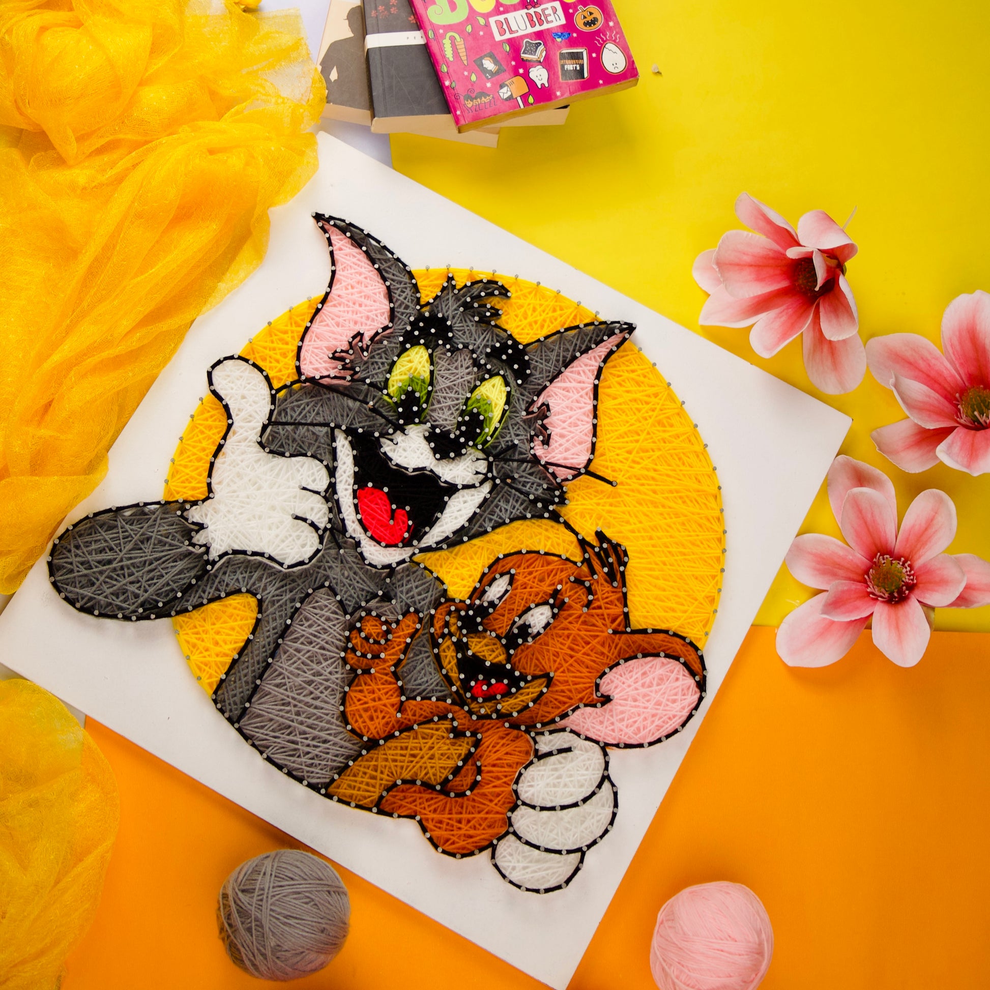 Colorful Tom & Jerry nail and thread art on white board, fun wall hanging for nostalgic fans.