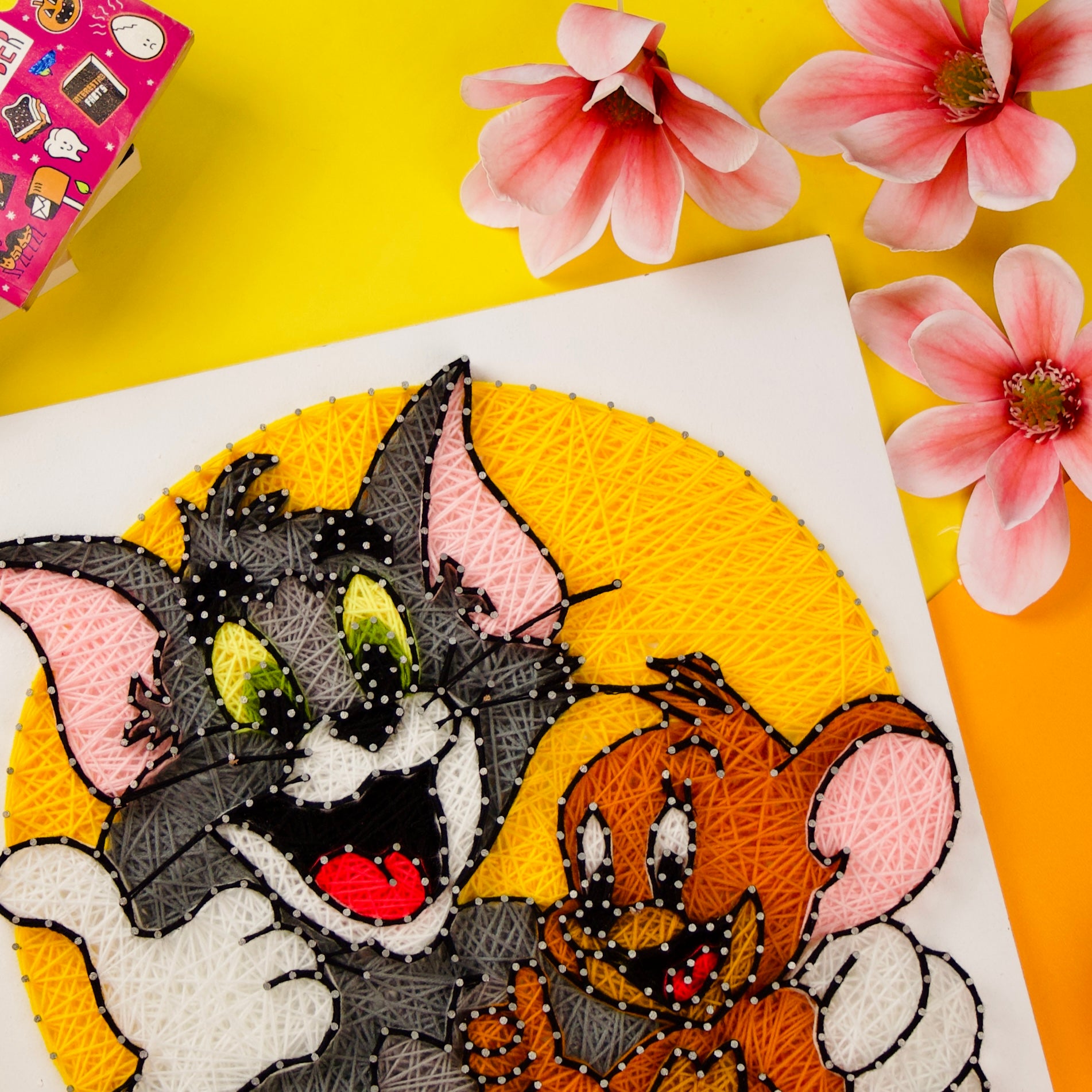 Playful Tom and Jerry string art design, handcrafted yarn decor for animation enthusiasts.